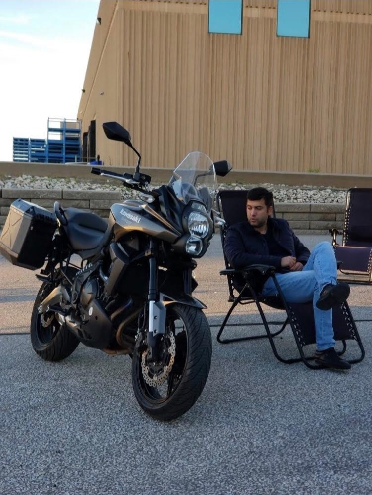 Ogulcan Aydogan sitting next to his Kawasaki motorcycle